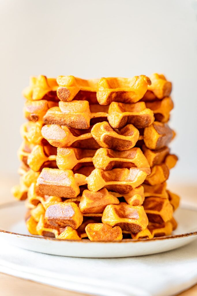 Gaufres dorées aux patates douces empilées sur une assiette.
